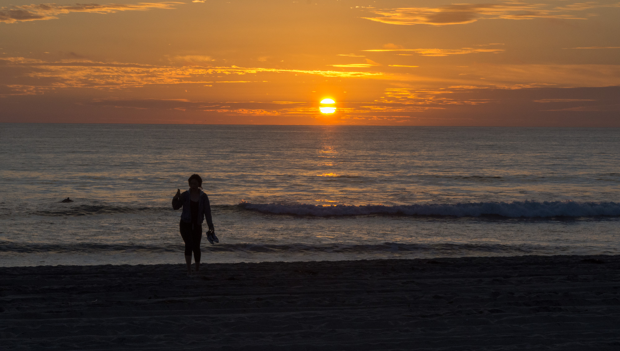 Lone walker on the beach at sunset