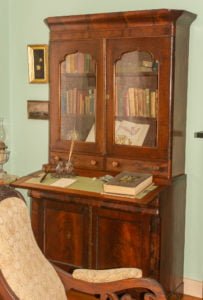 Early edition books on display in a beautifully restored secretary desk.